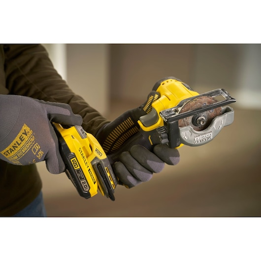 STANLEY SFMCM300D2 cordless mini circular saw held in gloved hands, yellow and black design.