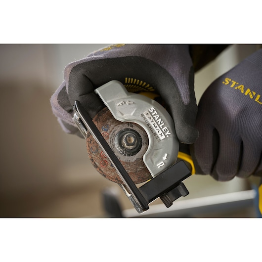 Photo of STANLEY SFMCM300D2 compact circular saw held with gloved hands, close-up side angle.