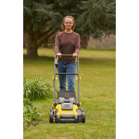 STANLEY SFMCMW2651M lawn mower front view in use outdoors, yellow and black, with grass trimmings bag.