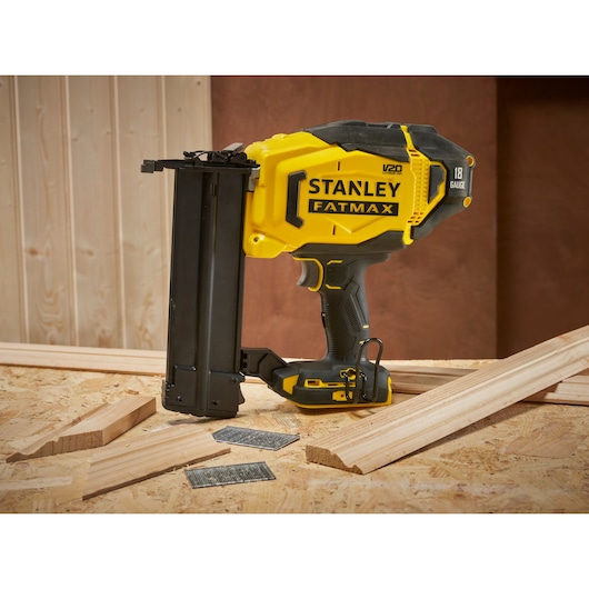 Photo of STANLEY SFMCN618B nailer Fatmax, 18 gauge cordless, on wood planks and nails, side angle.