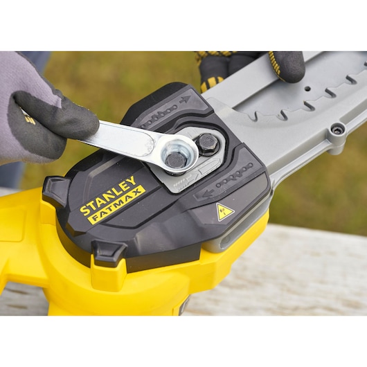 Photo of STANLEY SFMCPS515B chainsaw adjustment with wrench, close-up angle.