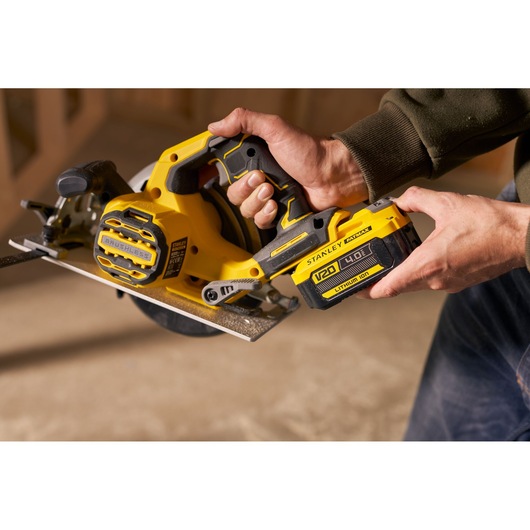 Photo of STANLEY SFMCS550B brushless cordless circular saw being held, yellow and black body, woodworking.