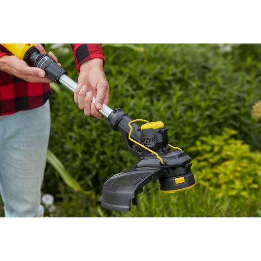STANLEY SFMCST933B grass trimmer close-up in use outdoors, showing black and yellow detailing.
