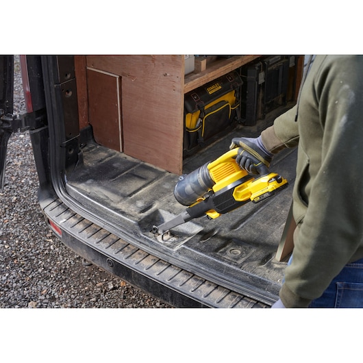 Photo of STANLEY SFMCVS001D1 cordless handheld vacuum in use on a van floor, yellow and black design.