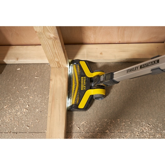 STANLEY SFMCVS001D1 cordless stick vacuum cleaning wood shavings in a corner, top view.