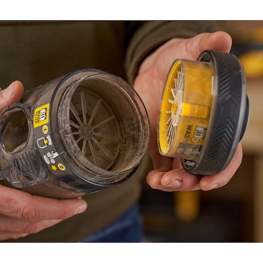 STANLEY SFMCVS001D1 vacuum filter and container held in hands, close-up with dust and filter details.