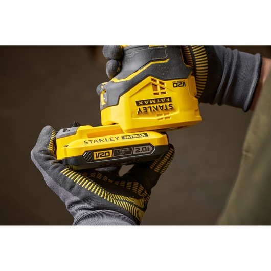 Photo of STANLEY SFMCW400B cordless sander with V20 FATMAX 2.0Ah lithium battery held by gloved hands.
