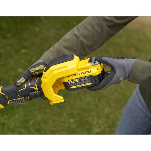 Photo of STANLEY SFMSTB930B power tool with V20 4.0Ah lithium-ion battery being held outdoors.
