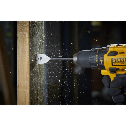 STANLEY STA88556 flat wood drill bit in action, drilling wood with shavings flying, side view, product photography