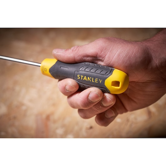 Photo of STANLEY STHT0-60358 screwdriver with yellow and black handle held in hand, close-up view.