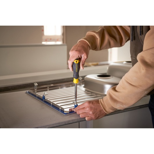 Photo of STANLEY STHT0-70885 screwdriver used to fasten metal brackets on a kitchen sink panel.