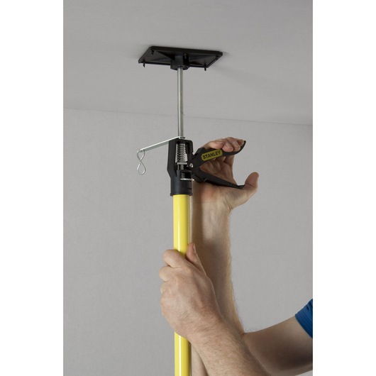 Photo of STANLEY STHT1-05932 support rod being used to brace a ceiling, close-up on handle and yellow pole.