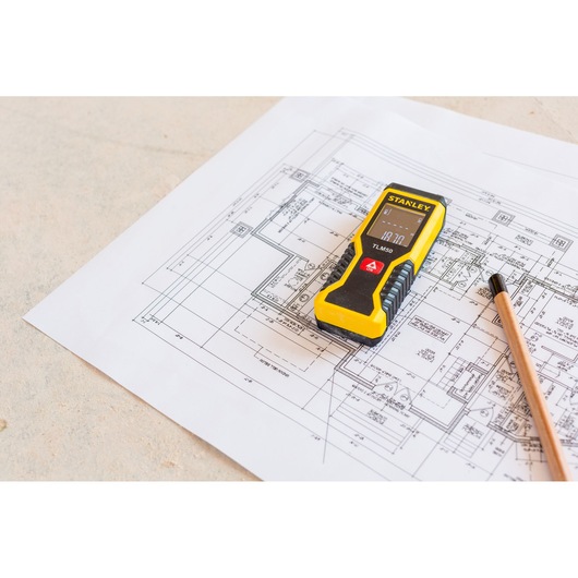 STANLEY STHT1-77409 laser distance measurer on architectural blueprint with pencil.