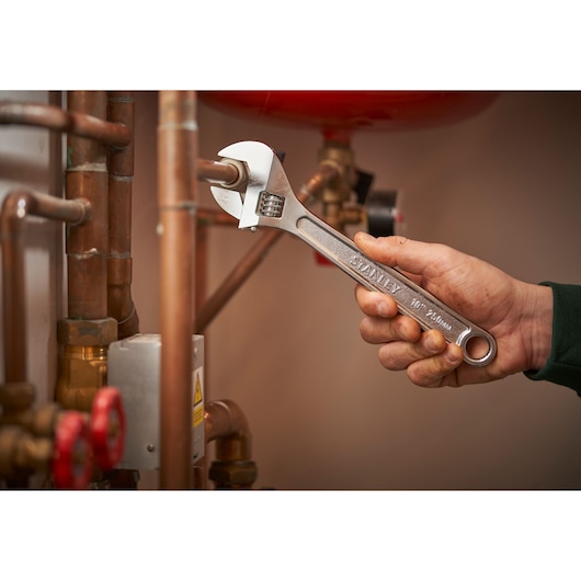 STANLEY STHT13121-0 adjustable wrench used on copper pipes, product held in hand.