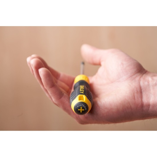 Stanley STHT16155-0 screwdriver with black and yellow handle held in hand, close-up photography.