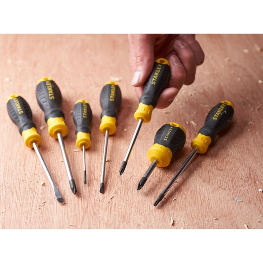 STANLEY STHT16155-0 screwdriver set with black and yellow handles on wooden surface, one held in hand.