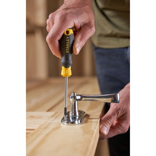 Stanley STHT16155-0 screwdriver used to fasten a door handle onto a wooden surface.