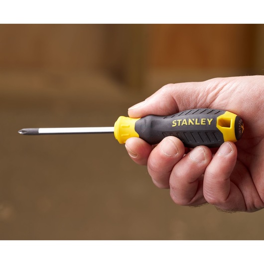 STANLEY STHT16155-0 screwdriver with black and yellow handle held in hand, side view.