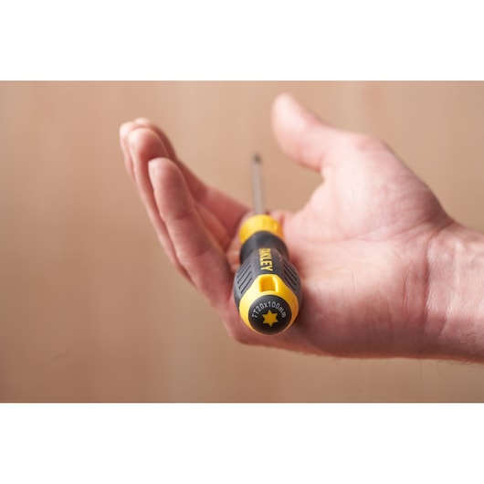 Photo of STANLEY STHT16179-0 screwdriver with black and yellow handle resting in an open hand.