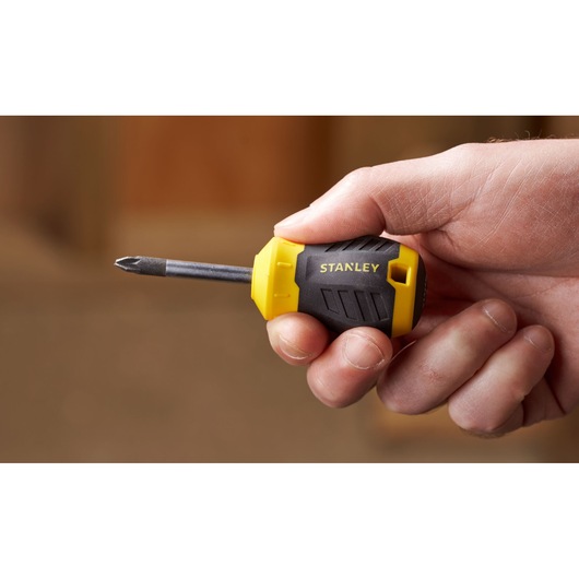 Photo of STANLEY STHT16196-0 stubby Phillips screwdriver with yellow and black handle held in hand.