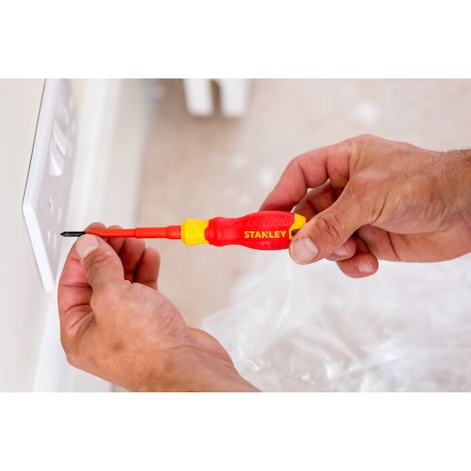 Stanley STHT60032-0 insulated screwdriver used on electrical outlet, close-up photo.