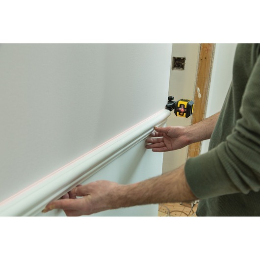 STANLEY STHT77498-1 laser level projecting line on wall during molding installation.