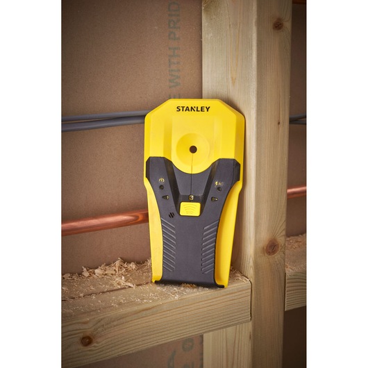 Stanley STHT77588-0 stud finder, yellow and black, angled vertically on wooden stud, photography.