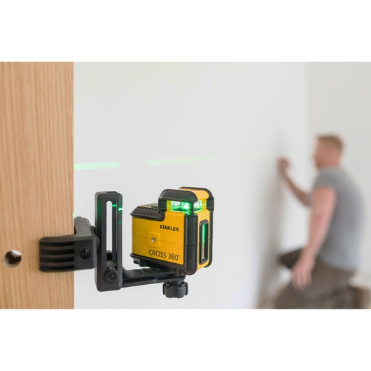STANLEY STHT77594-1 CROSS 360° laser level mounted on clamp projecting green lines in work area.