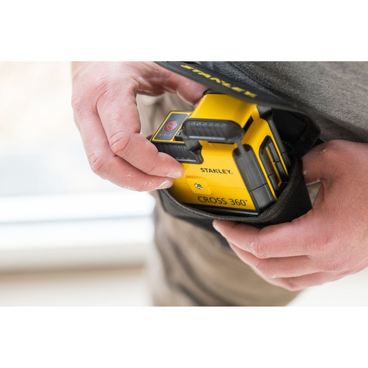 Photo of STANLEY STHT77640-1 CROSS 360° laser level being placed into a black carrying pouch by hand.