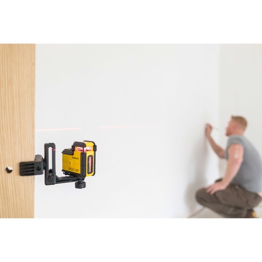 STANLEY STHT77640-1 laser level mounted on wood, projecting red line onto wall for alignment.