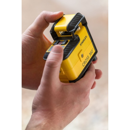 Photo of STANLEY STHT77640-1 CROSS 360 yellow laser level held in hands, close-up view.