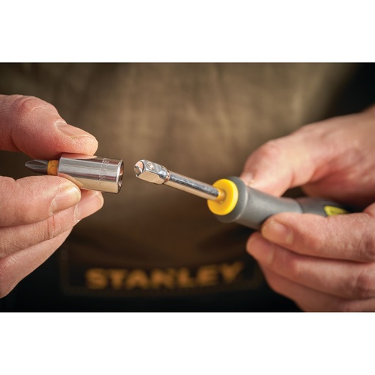 STANLEY STMT13910-0 hand holding ratchet screwdriver and detachable socket with bit, close-up photo.