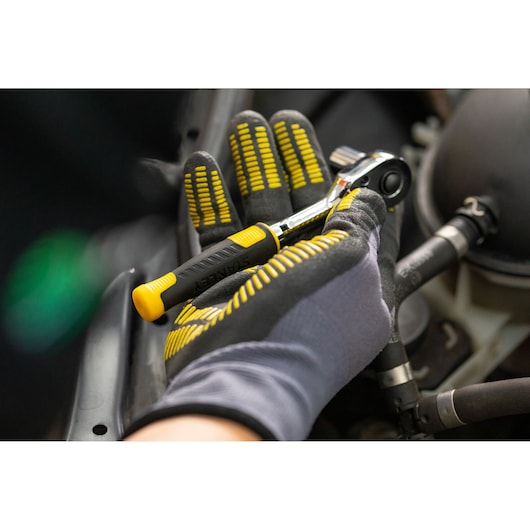 STANLEY STMT82663-0 ratchet tool with black and yellow handle held by gloved hand during automotive work.
