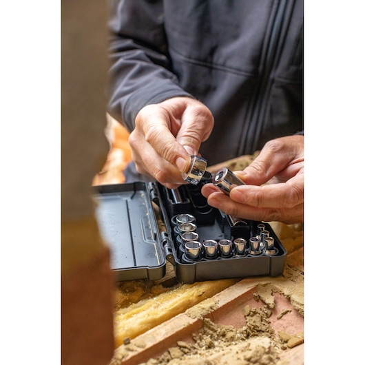 STANLEY STMT82672-0 socket set in black case, hands selecting a socket, close-up on worksite.