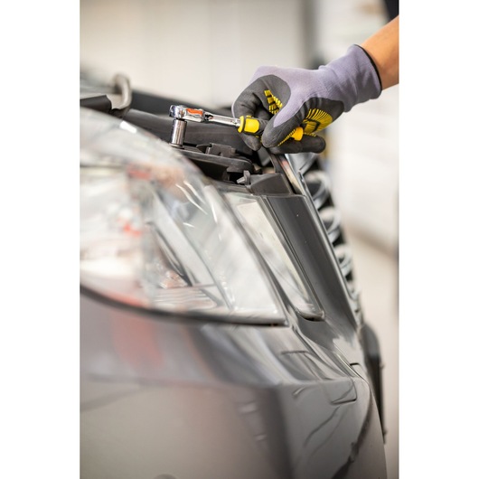 STANLEY STMT82828-1 ratchet screwdriver used to tighten bolt on car headlight, close-up.