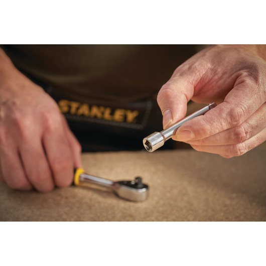 STANLEY STMT86006-0 socket extension bar held by hand, ratchet in background, close-up photo.