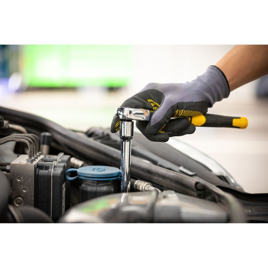STANLEY STMT86006-0 ratchet wrench used for car engine maintenance, close-up of gloved hand holding tool.