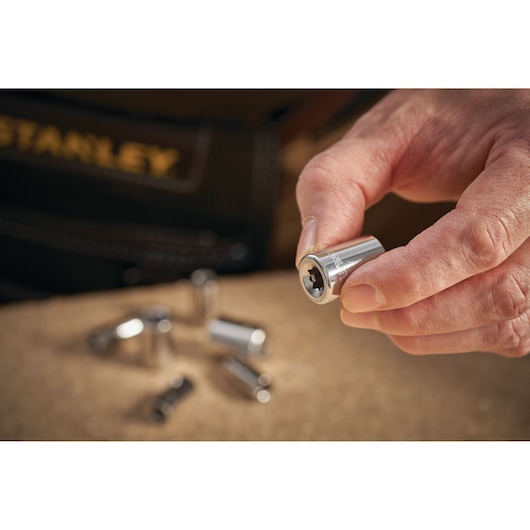STANLEY STMT86108-0 socket held in hand, chrome finish, with other sockets blurred in background.