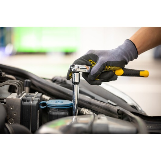 STANLEY STMT86206-0 ratchet wrench used on car engine, gloved hand grip, side angle, automotive tool.