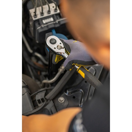 Photo of STANLEY STMT86207-0 ratchet wrench being used on car engine, worker wearing gloves.