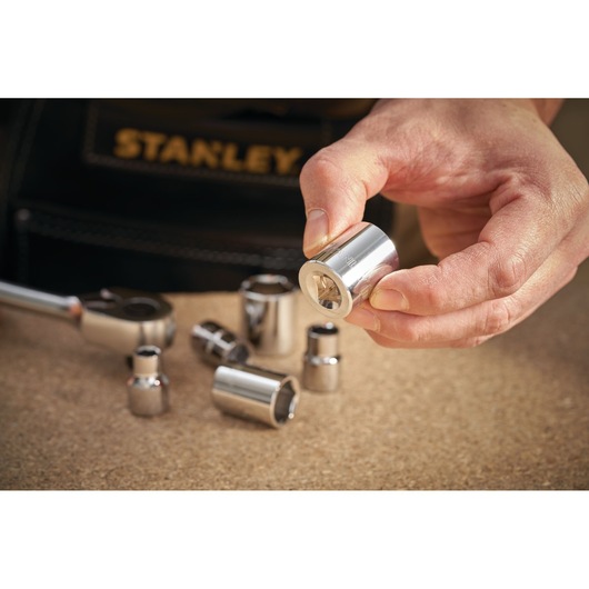 STANLEY STMT86317-0 socket set with chrome sockets on a workbench, hand holding one socket.