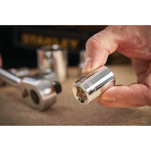 STANLEY STMT86518-0 socket held in hand with ratchet tool in background, close-up photography.