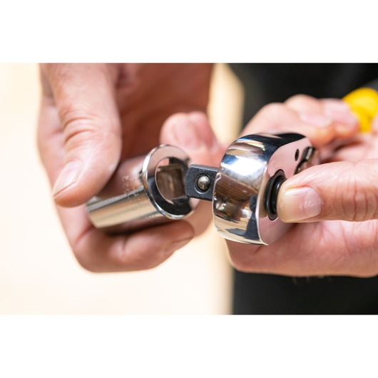 STANLEY STMT86518-0 photography of a hand attaching a chrome socket to a ratchet wrench.