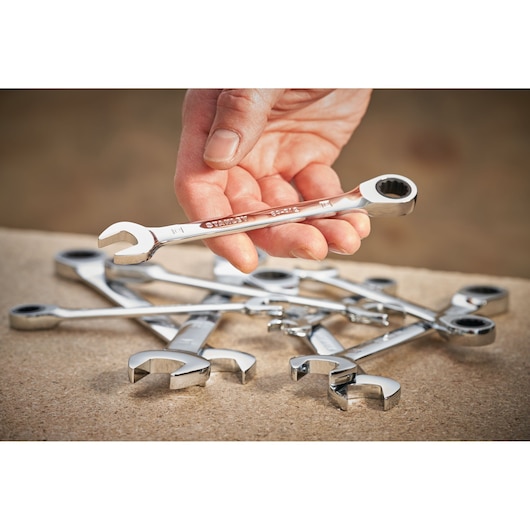 Photo of STANLEY STMT89919-0 ratcheting combination spanners set, chrome finish, held in hand, others on table.