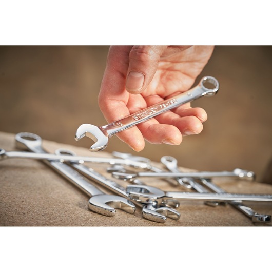 Photo of STANLEY STMT95787-0 chrome combination wrenches, one held in hand, others on work surface.