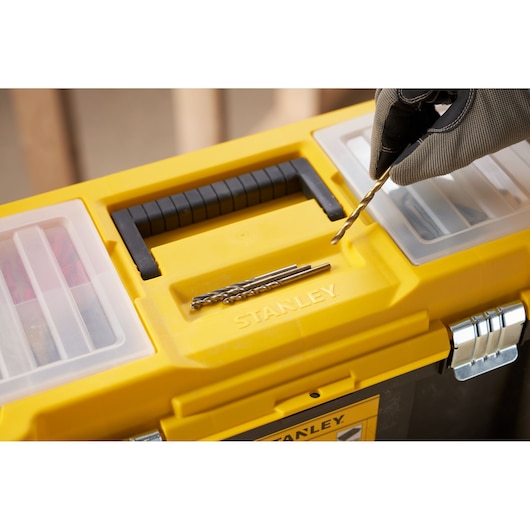 Photo of STANLEY STST75787-1 toolbox top view with hand holding drill bit and metal bits on yellow lid.
