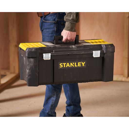 STANLEY STST82976-1 black and yellow toolbox being carried by a person in a workshop.