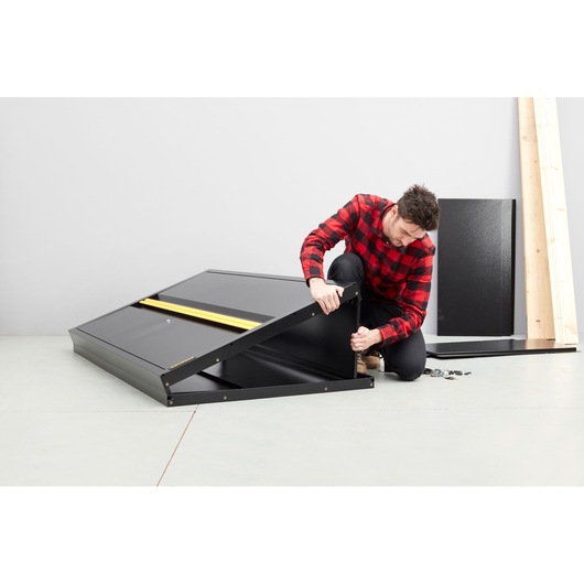 STANLEY STST97957-1 black metal cabinet assembly, side angle, with parts and person attaching panel.